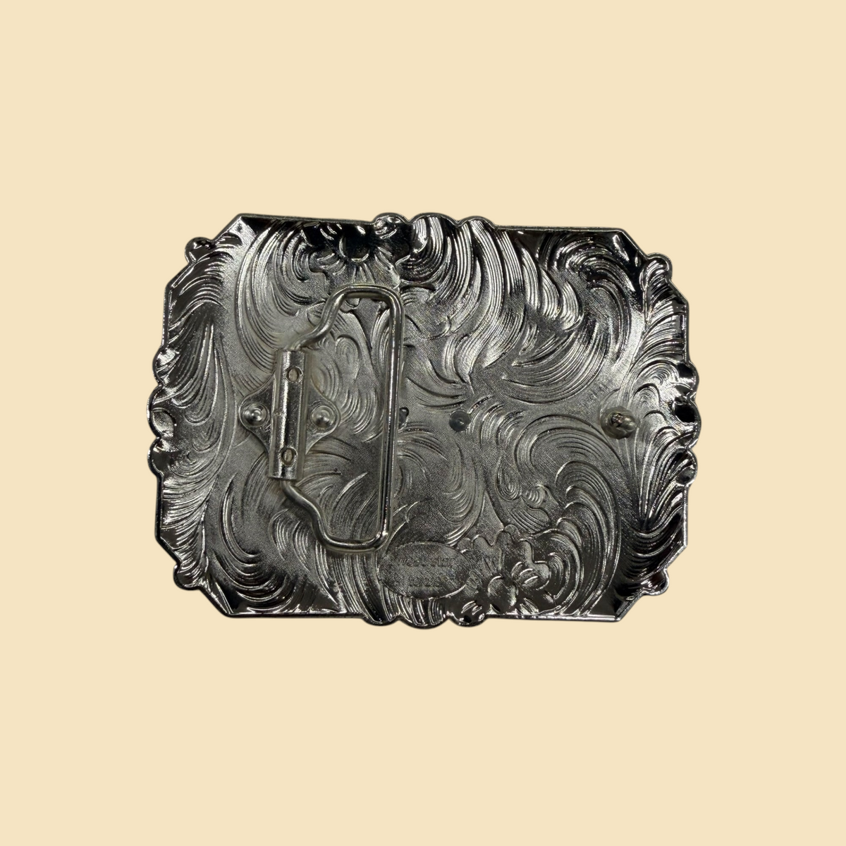 Back view of a Lopez Fashion rectangular belt buckle featuring intricate silver scrollwork and sturdy metal hardware.